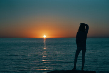 Fototapeta premium woman gesturing with her hands and sunset sea landscape beach