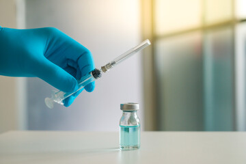 Close up doctor's hand holding medicine bottle and syringe for vaccine to patient on blue tone.Nurse using syringe are vaccination to patient for influenza protection.Medication treatment concept.