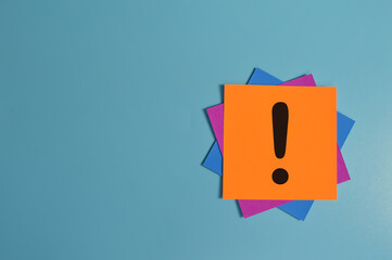 Exclamation mark drawn on memo note isolated on blue background. Copy space.