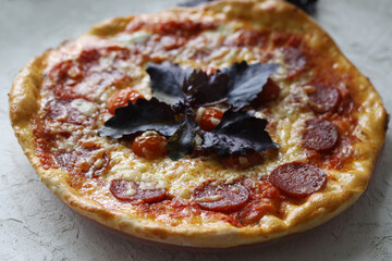 Delicious fresh pizza on a wooden table with basil leaves, mozzarella and cherry