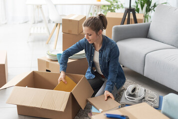 Young woman moving in her new apartment - obrazy, fototapety, plakaty