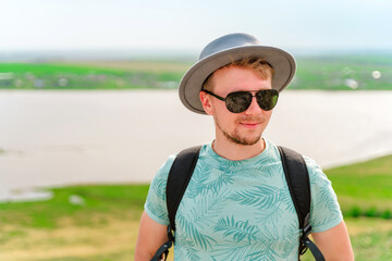 Young man in a hat walking on a hill, amazing summer landscape