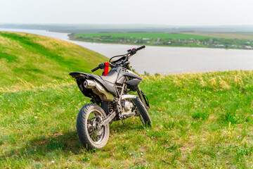 Fototapeta na wymiar The motorcycle stands on a hill overlooking a beautiful landscape with green meadows. Togliatti, Russia - 20 May 2021: