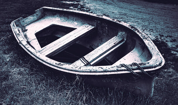 Vergessenes, leerstehendes altes Boot in freier Natur und vom Wetter angegriffen - Dark-Mood Style