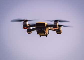 Drohne in der Luft in schwebender Position mit schönem Bokeh Effekt - Unbemanntes Luftfahrzeug - Flugzeug - Spielzeug - Quadkopter - Funkfernsteuerung  - obrazy, fototapety, plakaty