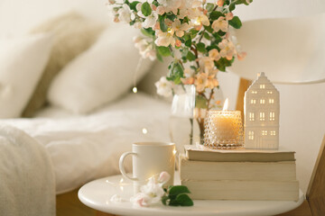 Book, hot cup tea, candle and vase with apple spring flowers.
