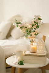 Book, hot cup tea, candle and vase with apple spring flowers.