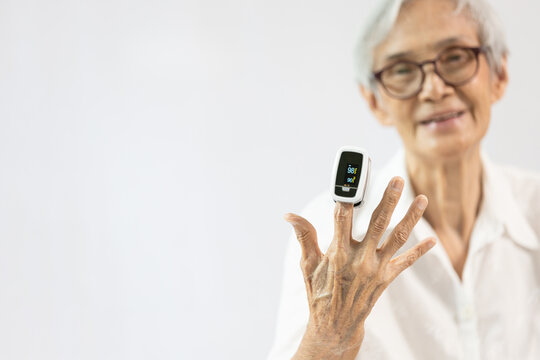 Hand of senior woman with an attached pulse oximeter on fingertip,old elderly measuring heart rate,checking oxygen saturation level in the blood,diagnosis of Coronavirus,COVID-19 at home,health care