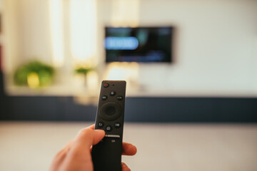 Selective focus image with a remote control and relaxing feet and tv in a modern living room. 