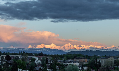 Fototapeta na wymiar Sunset light on mountain range eiger moench and jungfrau above bern suburbs