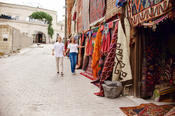 Couple in love buys a carpet and handmade textiles at an oriental market in Turkey. Hugs and cheerful happy faces of men and women
