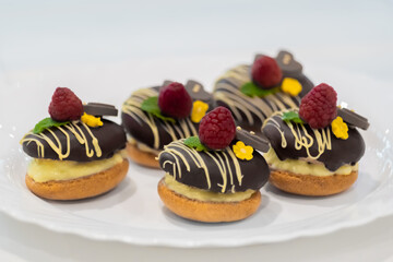 Close up: assortment of delicious fresh shortcrust tart cakes with cream, chocolate and fruits on white plate for sale at restaurant, cafe, bakery. Dessert, culinary and confectionery concept