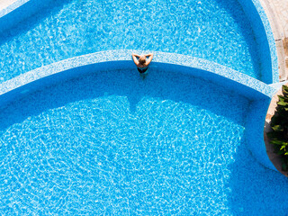Summer background. Aerial drone view of woman in pool in hotel. Summer holidays, enjoying summer vacations during quarantine.
