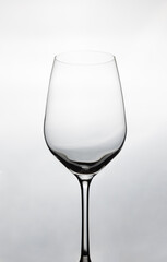 Close up and Front view of clear empty wine glass with beautiful lighting and white background shows elegant crystal glassware for luxurious beverage in restaurant, winery and celebrating party.