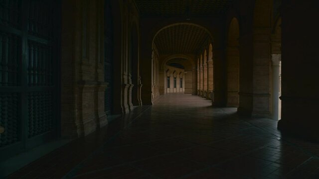 Walk through dark unrecognizable outdoor loggia in an ancient old building. University campus hall or museum. 