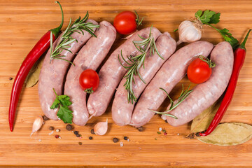 Top view raw pork sausages among spices on cutting board