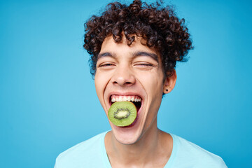 handsome man with kiwi curly hair in his mouth cropped view in blue background