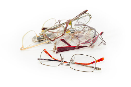 New eyeglasses for men against pile of old broken glasses