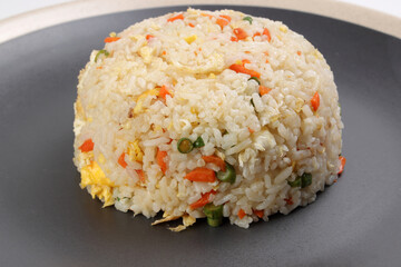Chinese style egg fried rice with carrot green spring onion on black plate off white rim over white background