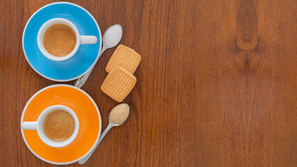 Fototapeta na wymiar Cups of coffee with cookies and spoons on wooden background from top