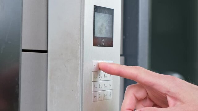 Male using intercom at residential building entrance. opens electronic code lock. man hand entering security system code, pressing button with index finger intercom device entrence door.
