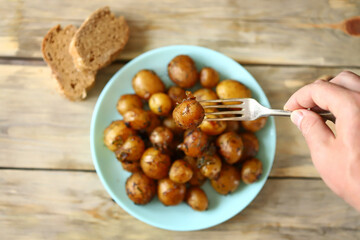 Whole fried potatoes. A plate of peeled baked potatoes. Appetizing baby potatoes with a golden crust.