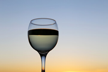 Glass with white wine on sunset background. Concept of celebration, evening party at resort, romantic dinner outdoors
