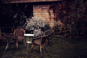 Fototapeta na wymiar Vintage styled image of an old garden in autumn with chairs and a table. 