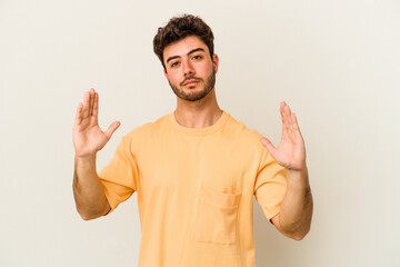 Fototapeta premium Young caucasian man isolated on white background holding something little with forefingers, smiling and confident.