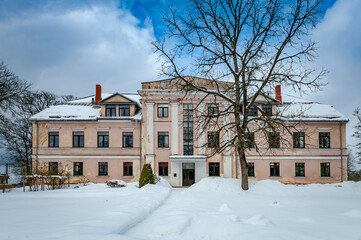 Path leads through the snowy park to the manor. Cere Manor, Latvia. The Cēre primary school is...