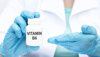 Vitamin B6 in white jar in hands in gloves doctor, medical concept