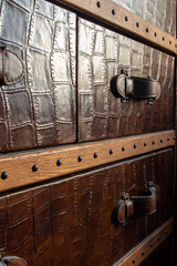 Extreme close-up of handle of steamer trunk covered with embossed leather and rivets
