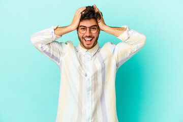Naklejka premium Young caucasian man isolated on blue background screaming, very excited, passionate, satisfied with something.