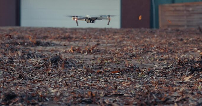 Drone blowing autumn leaves on a driveway