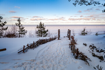 Footbridge over a dune at the beach in Latvia. Baltic Sea. Wooden steps leading to the frozen sea. Snowy winter landscape