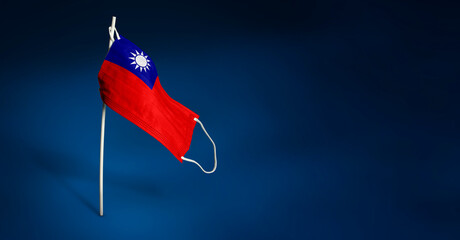 Taiwan mask on dark blue background. Waving flag of Taiwan painted on medical mask on pole. Concept of The banner of the fight against the epidemic coronavirus COVID-19