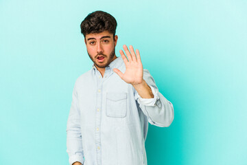 Young caucasian man isolated on blue background being shocked due to an imminent danger