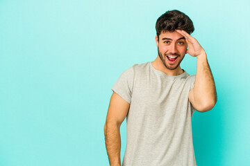 Young caucasian man isolated on blue background shouts loud, keeps eyes opened and hands tense.