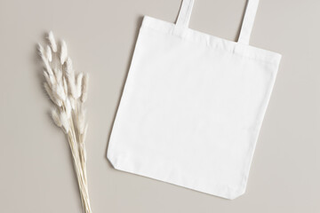 White tote bag mockup with a lagurus decoration on the beige background.