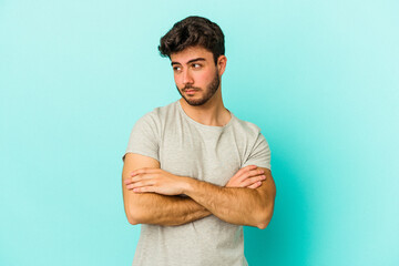 Young caucasian man isolated on blue background dreaming of achieving goals and purposes