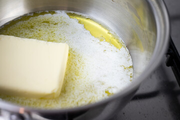 Roztapiające się masło w stalowym garnku. Gotowanie w kuchni. - obrazy, fototapety, plakaty