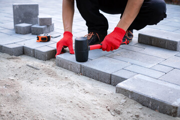 The master in yellow gloves lays paving stones