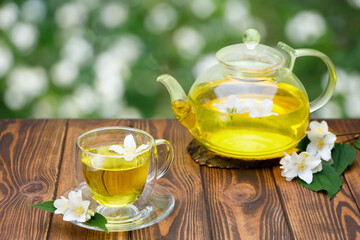 glass cup and teapot of green tea with jasmine flowers