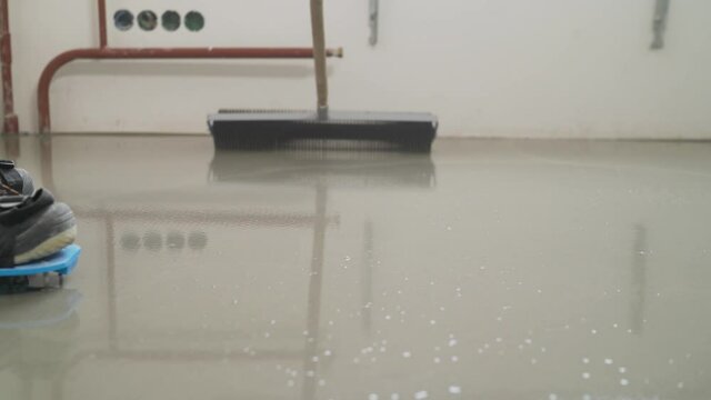Leveling the floor using spiked roller in empty room. Roll out the self-leveling floor using a needle roller.
