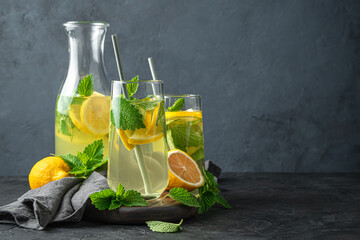 Refreshing lemonade with mint on a dark background. Side view, copy space. Summer drinks.