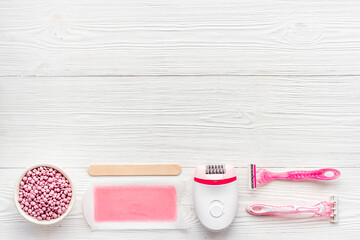 Flat lay of pink epilator with wax strips and razor. Spa cosmetic treatments.