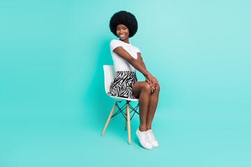 Photo of charming cute dark skin woman dressed casual outfit sitting chair smiling isolated...