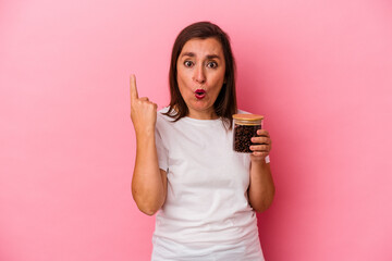 Middle age caucasian woman holding a coffee jar isolated on pink background having some great idea, concept of creativity.