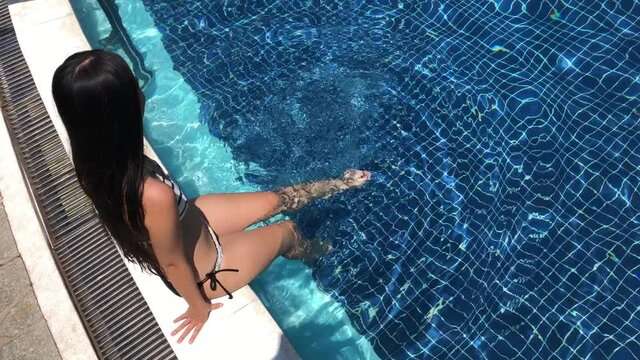 Girl in bikini swimming in an outdoor pool on a sunny day