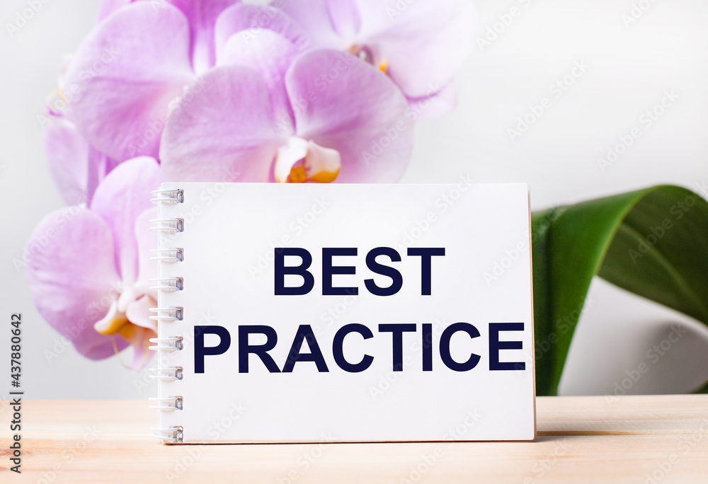 Aufkleber white blank notebook with the text best practice on the table against the background of a light pink